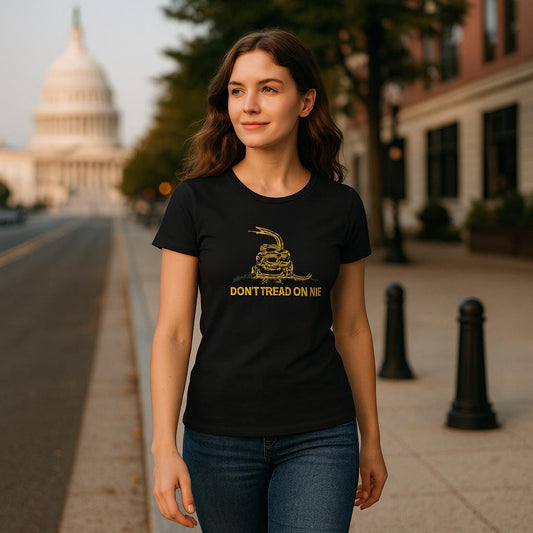 Woman walking confidently down a city street wearing a fitted black t-shirt featuring a yellow coiled rattlesnake and the text &quot;DON&#39;T TREAD ON ME.&quot; The U.S. Capitol building is visible in the background, suggesting a patriotic or political theme.