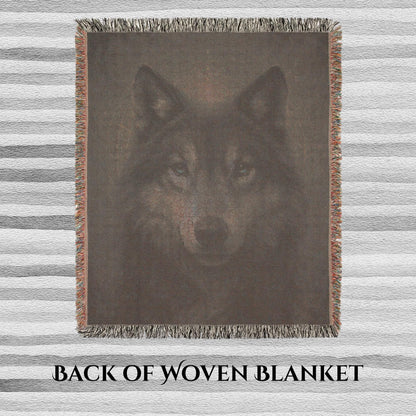 Back side of a woven blanket featuring a muted, reversed image of a wolf&#39;s face with visible thread texture. The blanket has multicolored fringe edges and is laid flat on a striped surface. Text at the bottom reads “BACK OF WOVEN BLANKET.”
