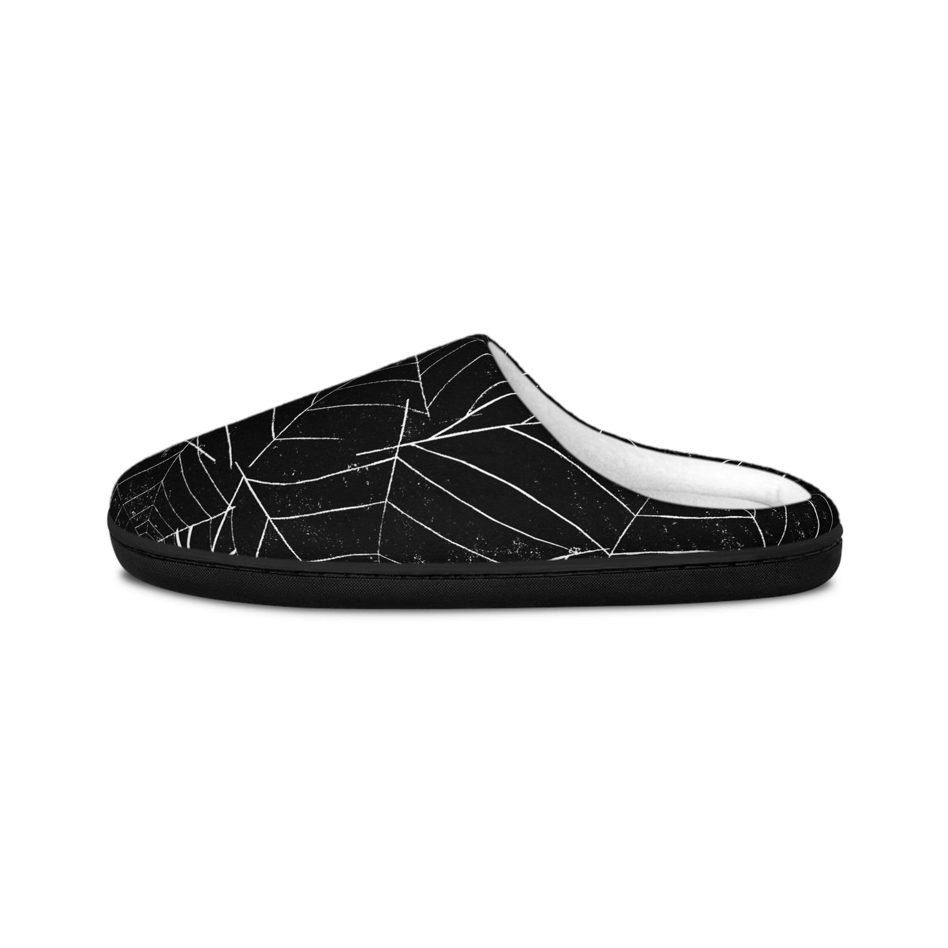 A side view of a black slipper featuring a white spiderweb design, displayed on a plain white background. The slipper has a cozy white interior lining and a low-back, slip-on style, combining comfort with a spooky Halloween-themed look.