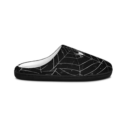 A side view of a black slipper with a white spiderweb and spider design, displayed on a plain white background. The slipper features a soft white interior lining and a low-back, slip-on silhouette, offering a cozy and festive Halloween-themed style.