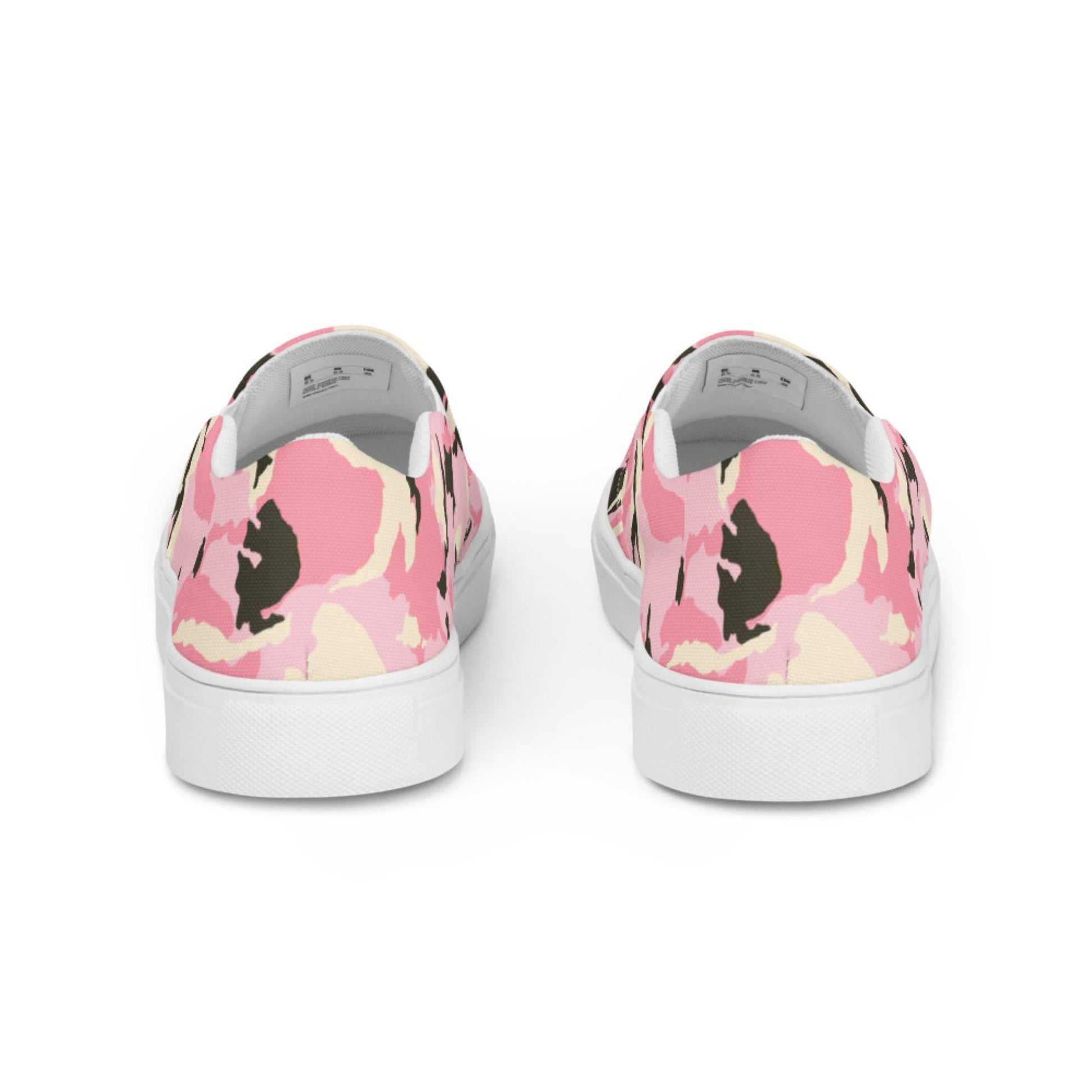 Rear view of a pair of slip-on sneakers featuring a pink camouflage pattern with cream and black accents, set against a white background, showcasing the back heel design and white rubber soles.