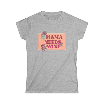 Front view of a heather gray women&#39;s fitted t-shirt with a playful graphic design that reads &quot;Mama Needs Wine&quot; in bold pink lettering. The design features a champagne glass and whimsical flowers in soft pastel tones, centered on a peach-colored rectangular background. The shirt is laid flat against a white backdrop.