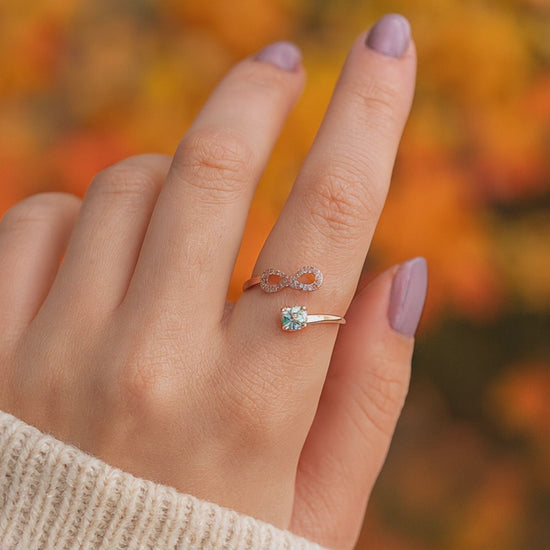 A woman wearing a rose gold infinity ring on her pointer finger.